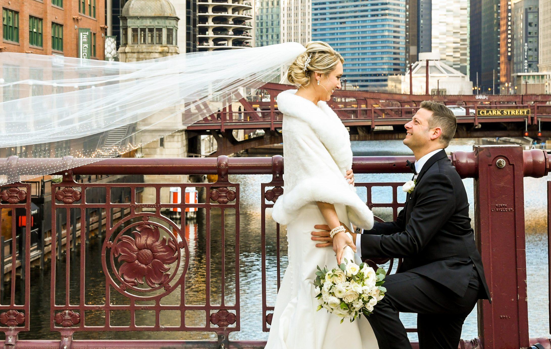 groom kneeling down and looking at the bride while bride is looking at him and similing